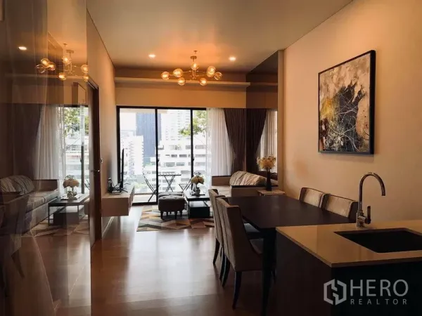 Condominium for rent in Watthana, Bangkok - Open-plan living and dining area with modern pendant lights and large sliding windows facing the skyline.