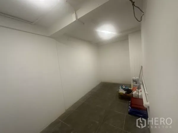 零售空间 出租 - 小型后室/储物区，深色地砖并放置物品。