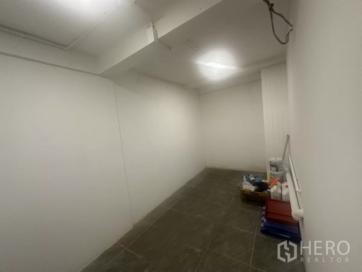 零售空间 出租 - 小型后室/储物区，深色地砖并放置物品。