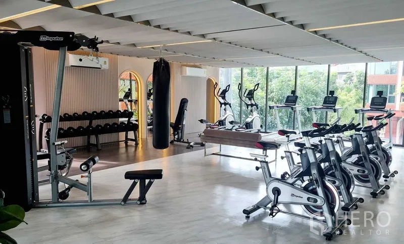 Condominium for rent in Phra Khanong, Bangkok - Bright fitness center with bikes, treadmills, weight rack, and a punching bag.