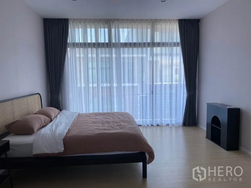 Townhouse for rent in Saphan Sung, Bangkok - Spacious bedroom with large glazed wall, sheer curtains and minimalist furnishings.