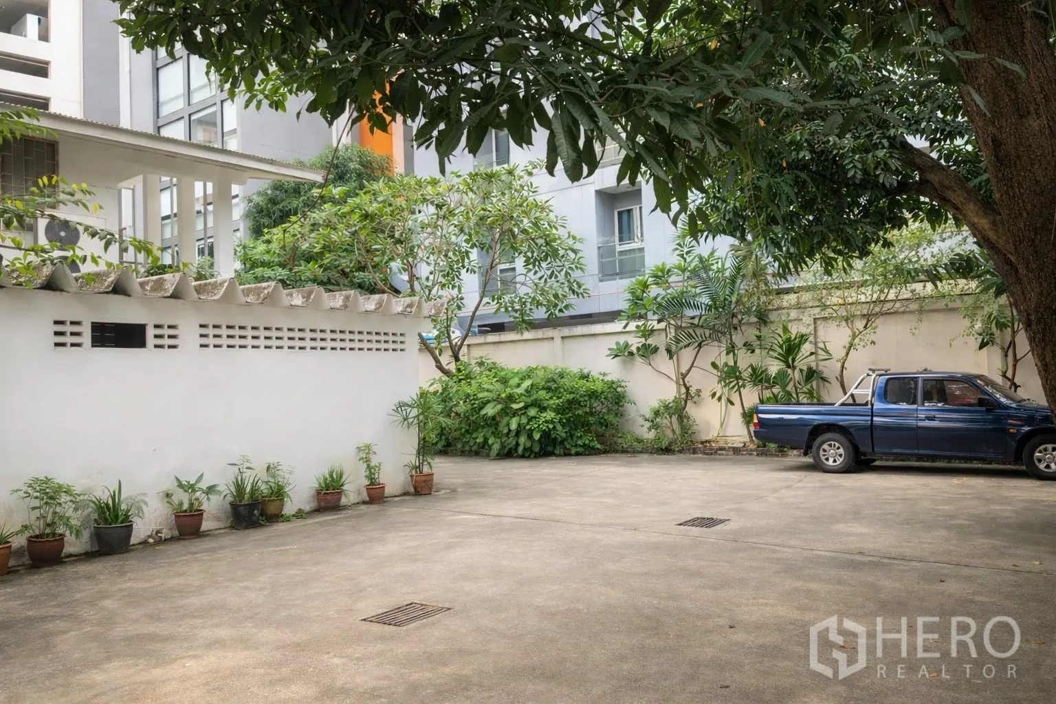 零售空间 for rent in Watthana, Bangkok - 素坤逸零售物业的院内停车区，树荫与围墙环绕。