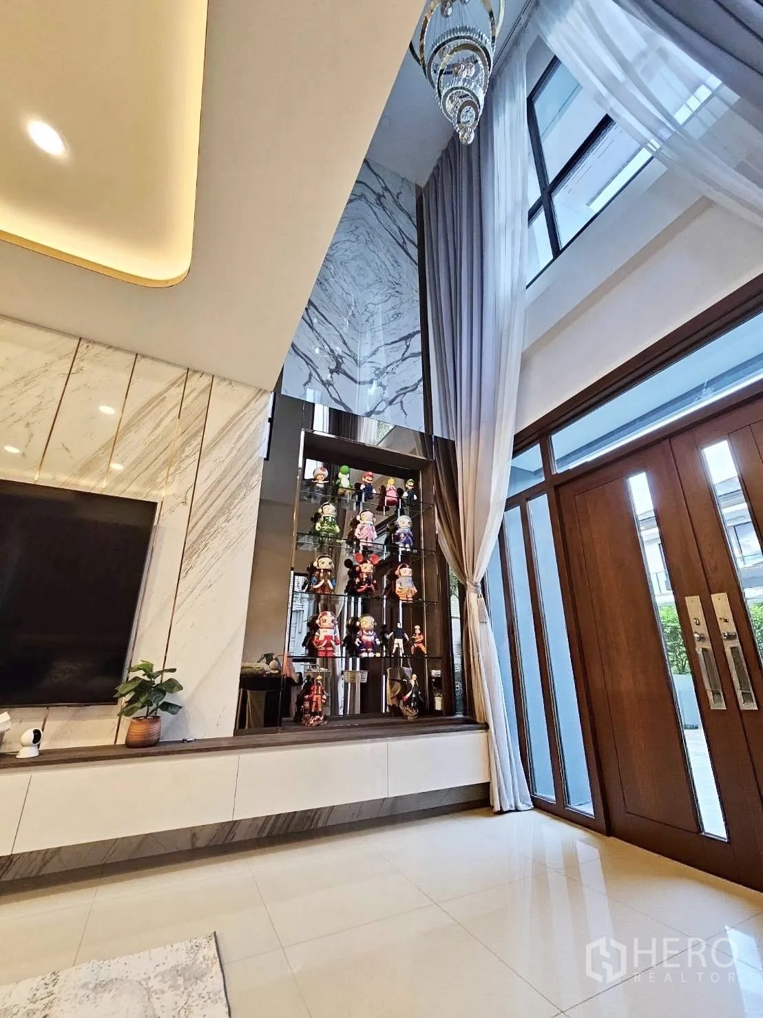 Detached House for rent in Wang Thonglang, Bangkok - Double-height entry area with display cabinet, tall windows, and wooden front doors.