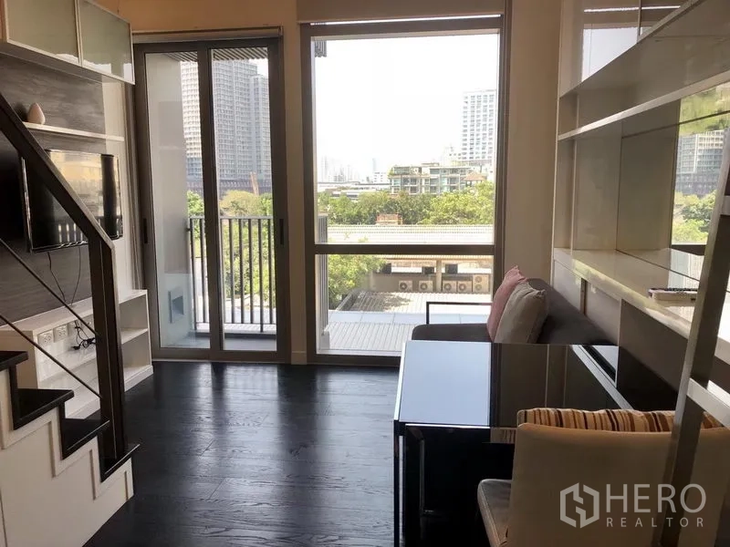 公寓 出租在Khlong Toei, Bangkok - 客厅落地窗与阳台门，采光充足并见城市景观。