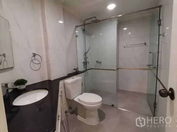 อพาร์ทเมนท์ ให้เช่า - ห้องน้ำสมัยใหม่ ผนังลายหินอ่อน พร้อมฝักบัวเรนชาวเวอร์ในตู้กระจกและเคาน์เตอร์อ่างล้างหน้า