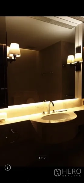 Condominium for rent in Watthana, Bangkok - Modern bathroom vanity with wide mirror, underlit countertop and wall sconces.