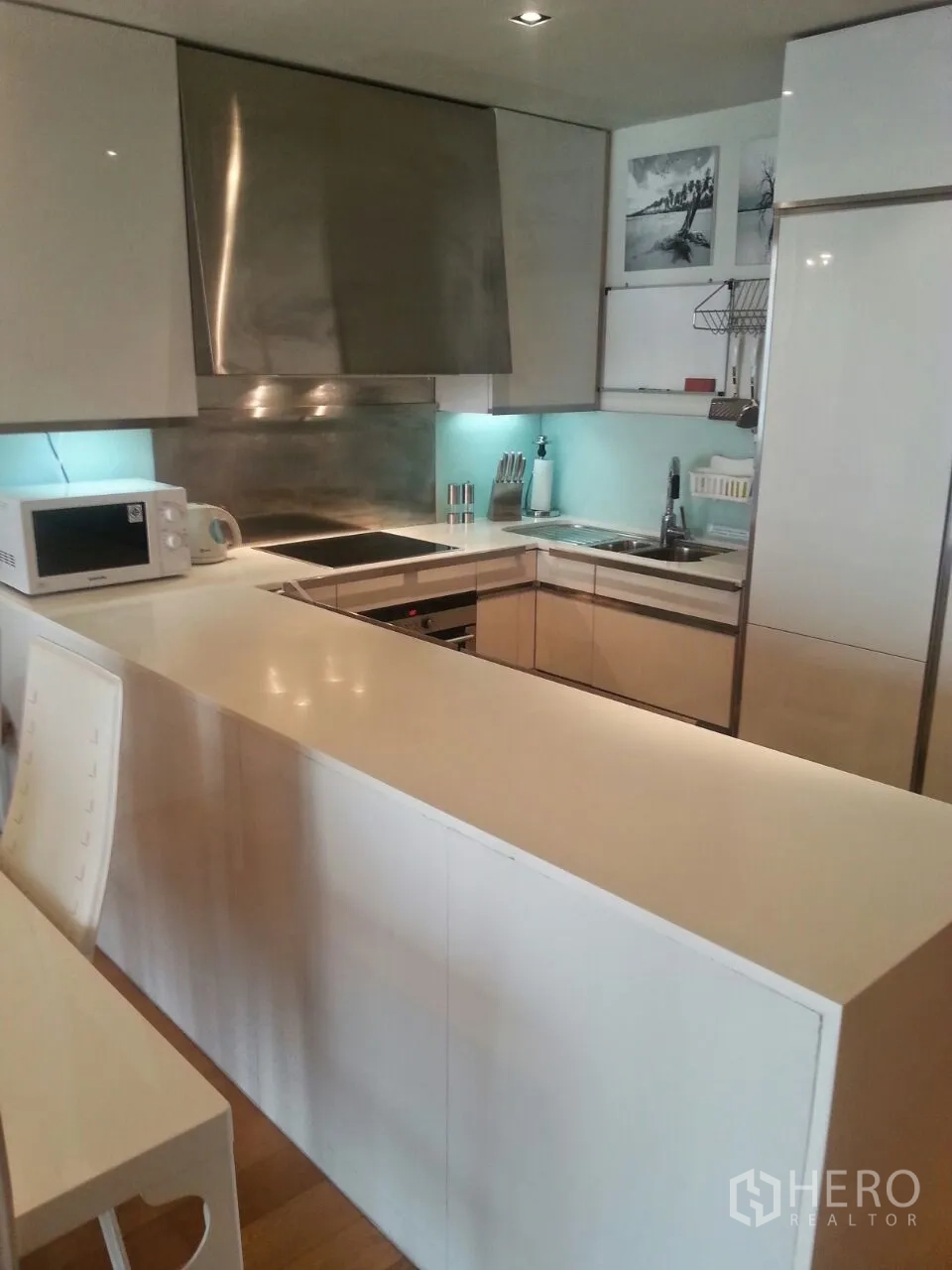 Condominium for rent or sale in Sathon, Bangkok - U‑shaped kitchen with long island, stainless backsplash and integrated appliances.