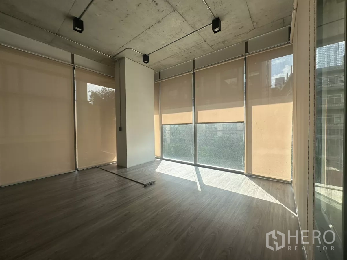 零售空间 出租 - 明亮转角区，米色卷帘与环绕落地窗，引入大量自然光。