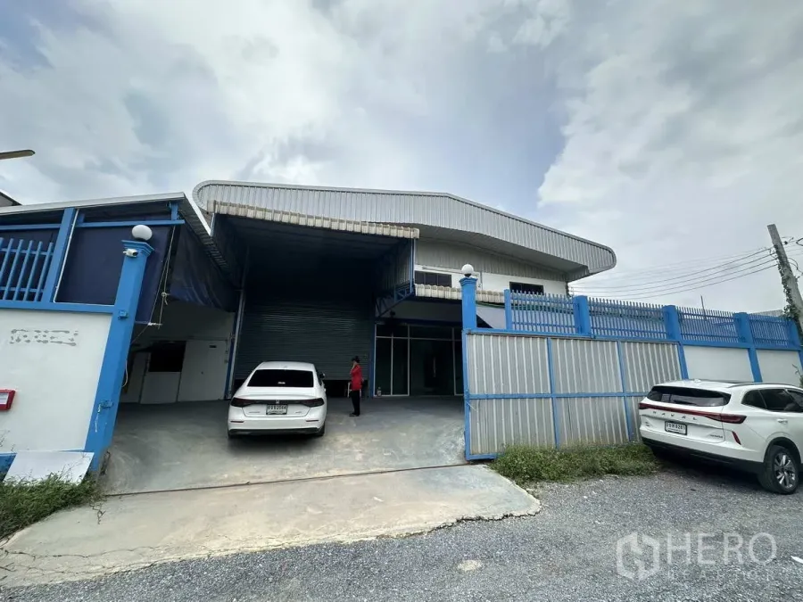 工厂 出租或出售在Bang Yai, Nonthaburi - 工厂正门外观，蓝色围栏、装卸雨棚与卷帘门。