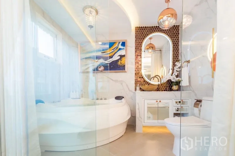 联排别墅 出租在Lat Phrao, Bangkok - 豪华浴室，圆形浸泡浴缸，大理石墙面，金色龙头与椭圆镜。