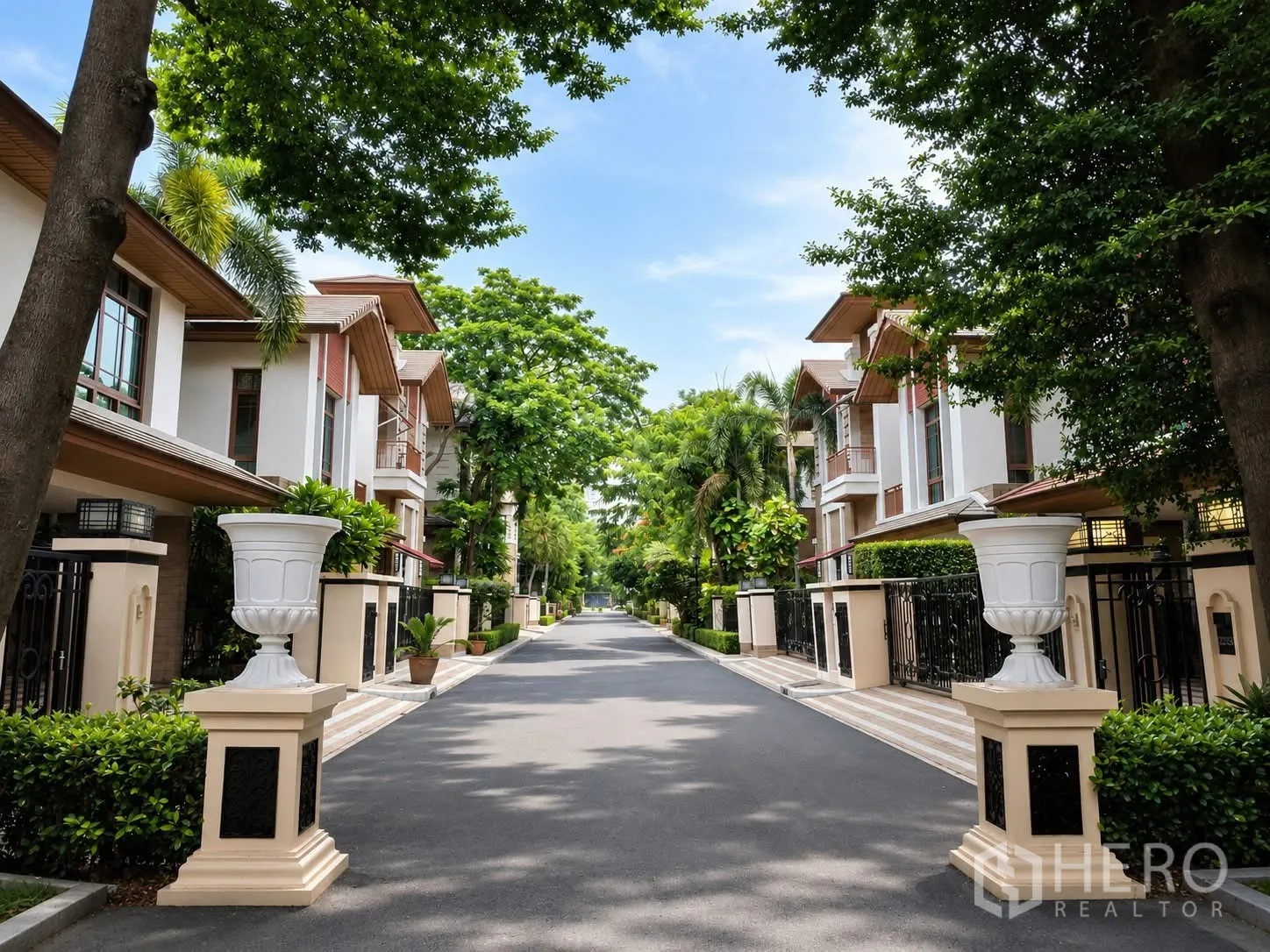 Detached House for rent in Watthana, Bangkok - Gated lane with villas and decorative pillars along a shaded street.