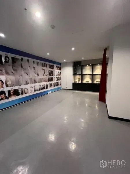 零售空间 出租在Watthana, Bangkok - 展示区带照片拼贴特色墙、陈列柜与红色帘隔间。