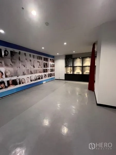 零售空间 出租在Watthana, Bangkok - 展示区带照片拼贴特色墙、陈列柜与红色帘隔间。