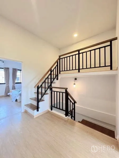 Townhouse for rent in Min Buri, Bangkok - Staircase and upper landing with black metal railings and warm pendant lighting.