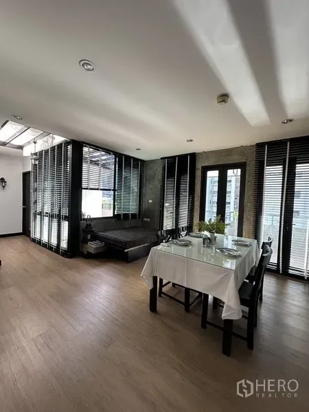 公寓 出租在Khlong Toei, Bangkok - 餐区一角，大片窗户与百叶帘，配休闲躺椅。