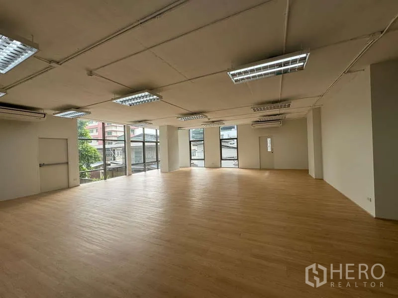 Office Space for rent in Sathon, Bangkok - Bright corner office featuring floor-to-ceiling windows, wood floors, ceiling lights and wall-mounted air conditioners.