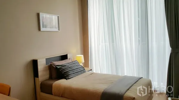 คอนโด ให้เช่าหรือขายในKhlong Toei, Bangkok - ห้องนอนเล็กเตียงเดี่ยว ข้างผ้าม่านโปร่งสูงจรดเพดาน แสงธรรมชาติสว่างสบาย