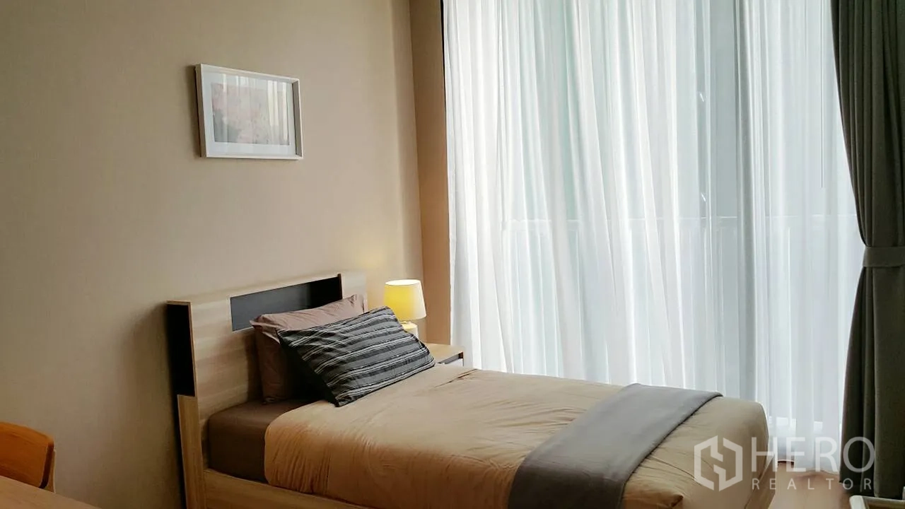 คอนโด ให้เช่าหรือขายในKhlong Toei, Bangkok - ห้องนอนเล็กเตียงเดี่ยว ข้างผ้าม่านโปร่งสูงจรดเพดาน แสงธรรมชาติสว่างสบาย