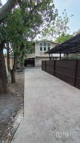 Detached House for rent in Phaya Thai, Bangkok - Long gated driveway leading to the house, trees and covered parking area.