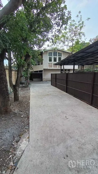 独立式住宅 出租在Phaya Thai, Bangkok - 带门禁的长车道通往房屋，树木成荫并设有有顶停车位。