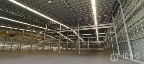 货栈 出租在Nikhom Phatthana, Rayong - 宽阔的清晰跨距钢结构，带行车轨道与屋面采光的仓库内部。