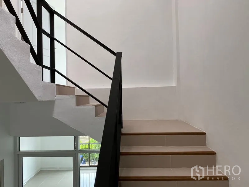 Home Office for rent in Wang Thonglang, Bangkok - Staircase with black metal handrail and light-tiled steps.