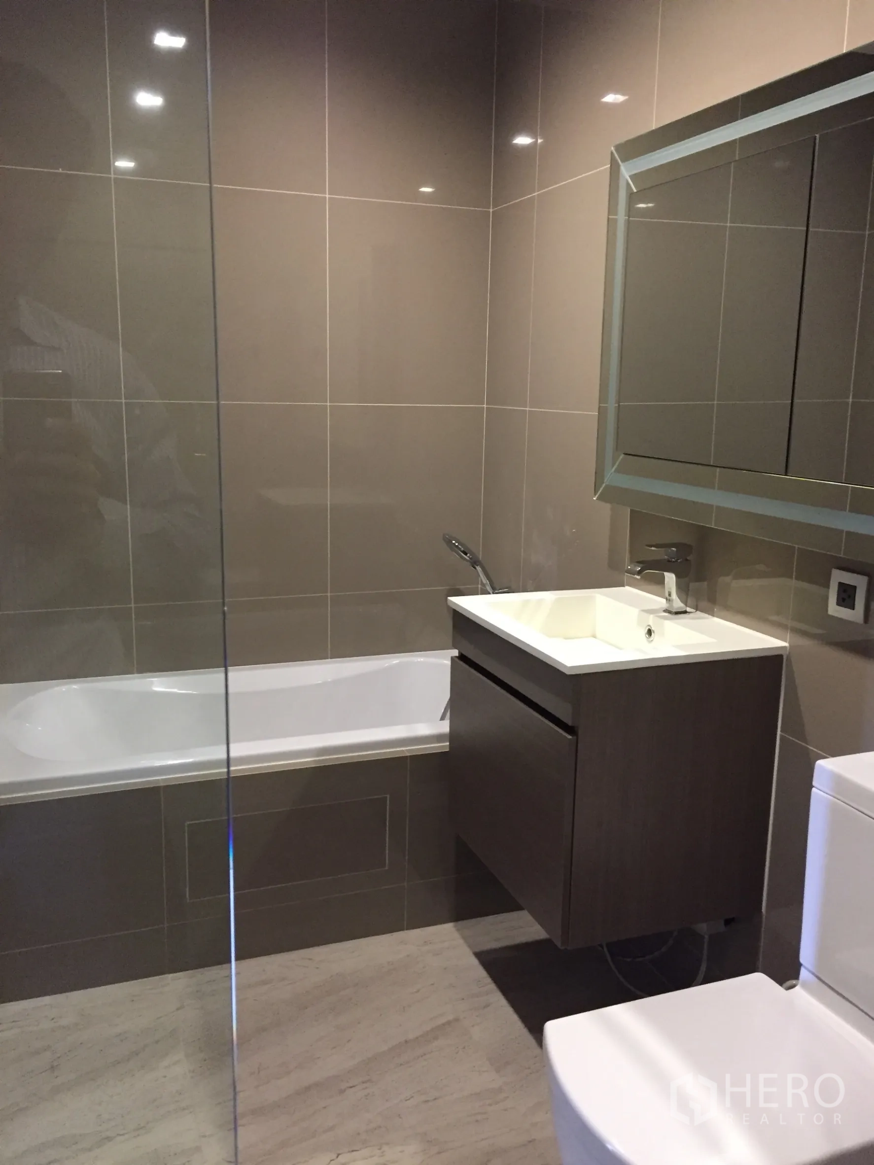 Condominium for rent in Watthana, Bangkok - Contemporary bathroom with floating vanity and bathtub beside glossy tiled walls.