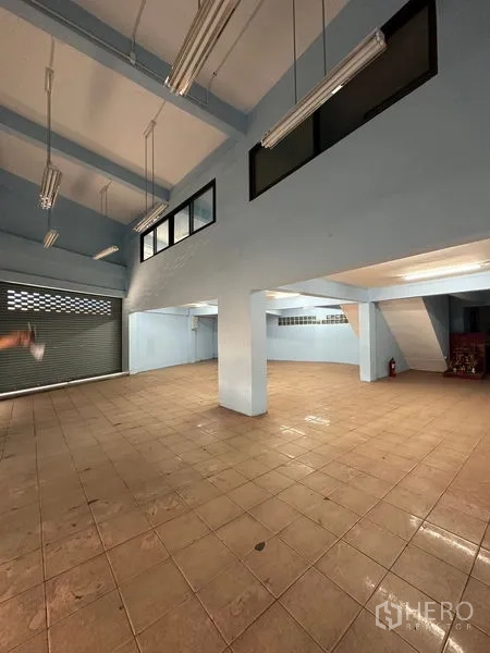 店屋 出租在Bang Na, Bangkok - 一层大厅宽敞，层高较高，立柱与日光灯，配有卷闸门。