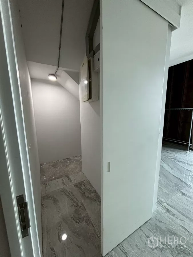 Condominium for sale in Bang Kho Laem, Bangkok - Compact storage closet with sliding door, electrical panel and grey tile floor.