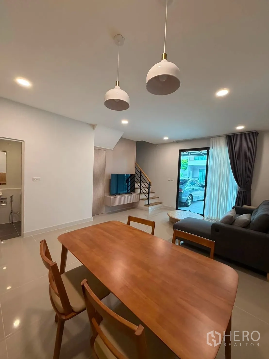 Townhouse for rent in Bang Phli, Samut Prakan - Dining space with pendant lights, wooden table and chairs near the living area.