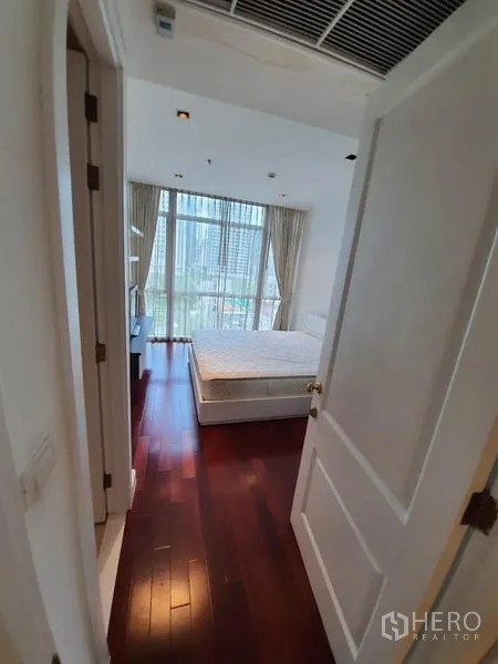 คอนโด ให้เช่าในPathum Wan, Bangkok - มุมมองจากประตูเข้าสู่ห้องนอน พื้นไม้และหน้าต่างสูงพร้อมม่านโปร่ง