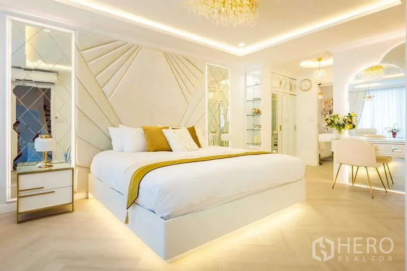 Townhouse for rent in Lat Phrao, Bangkok - Spacious white-and-gold suite bedroom with feature wall and vanity area.