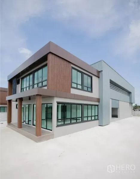 Factory for rent or sale in Nakhon Pathom - Corner view of modern two-storey office attached to a steel-clad warehouse building.