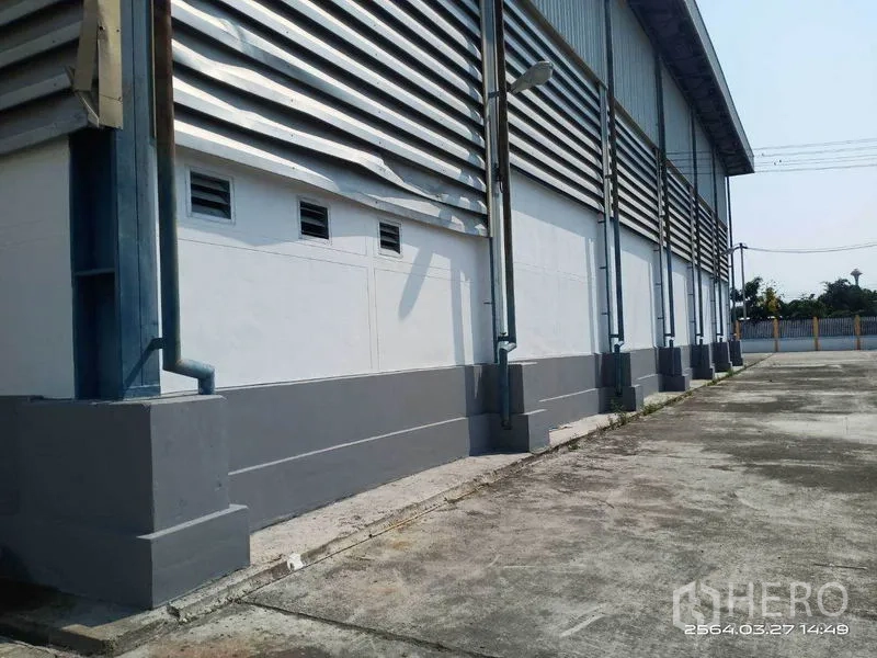 Warehouse for rent in Bang Bo, Samut Prakan - Wide concrete yard along the perimeter wall with overhead power lines.