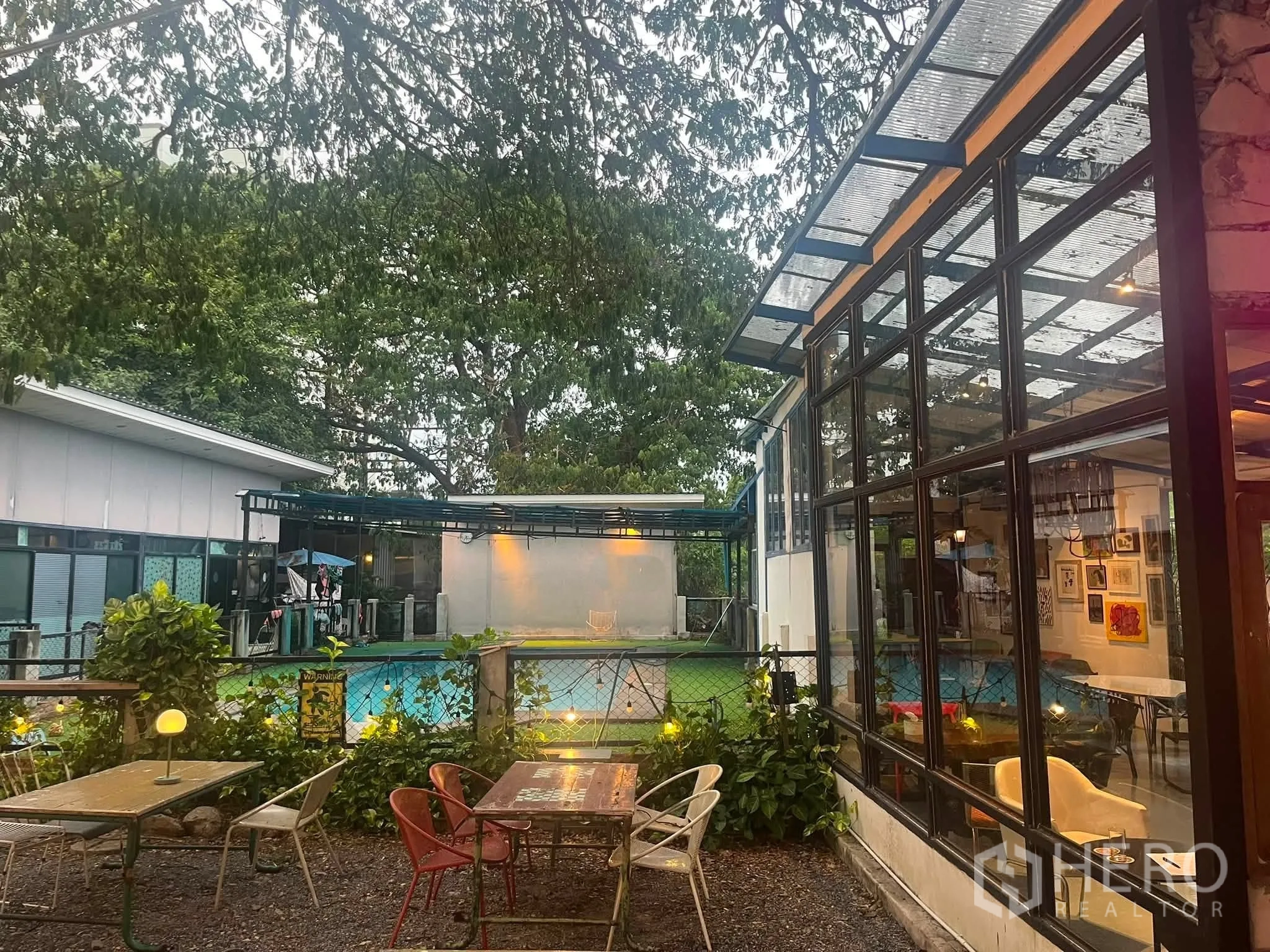 零售空间 for rent in Watthana, Bangkok - 花园庭院邻接玻璃外墙，设户外座位并可望见围栏外的泳池。