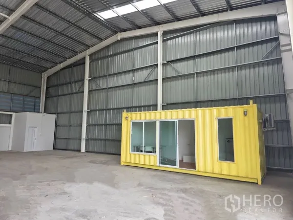 货栈 出租在Khlong Luang, Pathum Thani - 仓库内部空间高挑，金属屋顶，带黄色集装箱办公室与玻璃门。