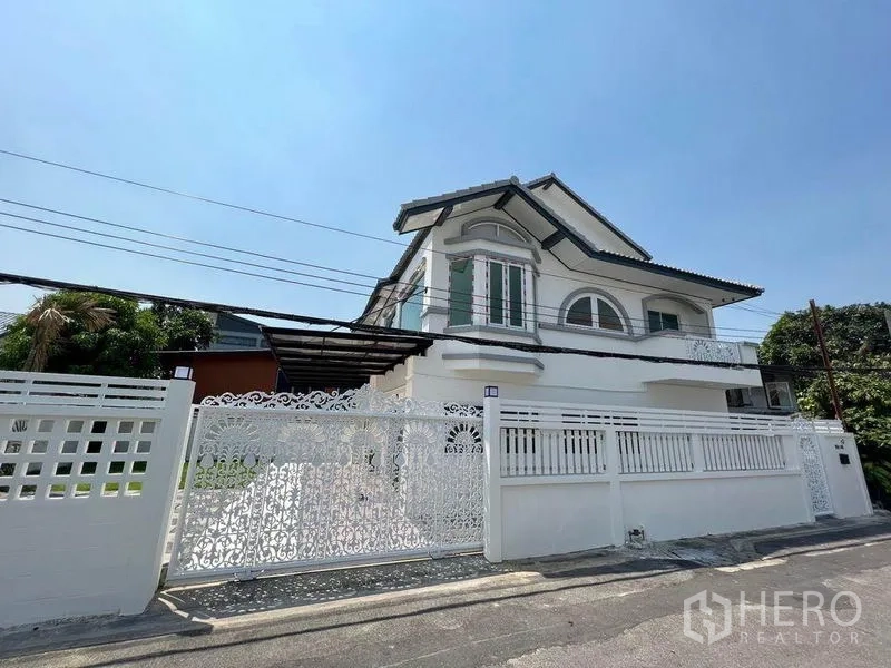 Detached House for sale in Bang Bon, Bangkok - Corner exterior view with ornate white gate and secure boundary wall of the home.