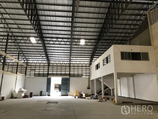 Warehouse for rent in Bang Phli, Samut Prakan - Spacious warehouse interior with high steel-truss roof, polished concrete floor and mezzanine office with stairs.