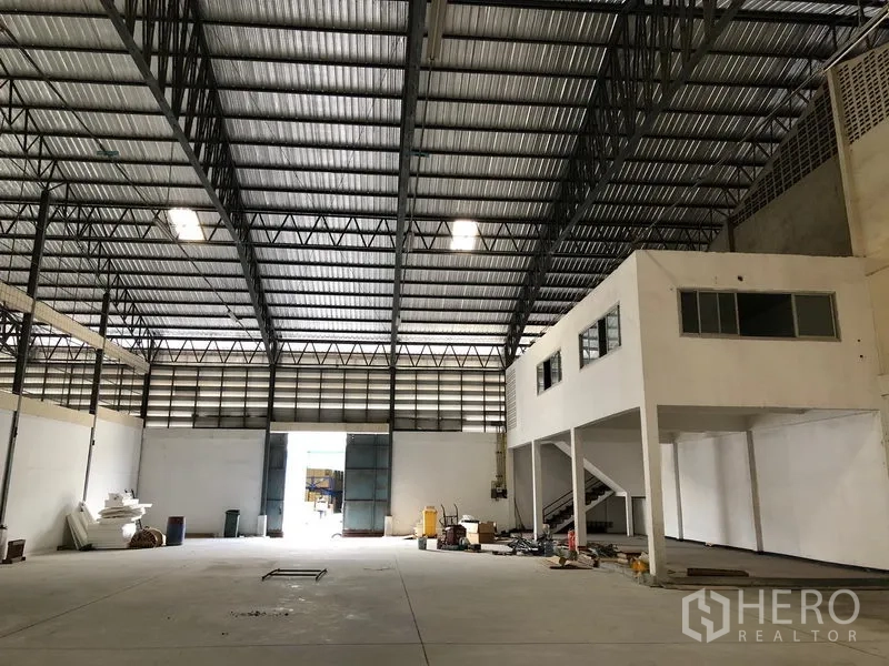 Warehouse for rent in Bang Phli, Samut Prakan - Spacious warehouse interior with high steel-truss roof, polished concrete floor and mezzanine office with stairs.