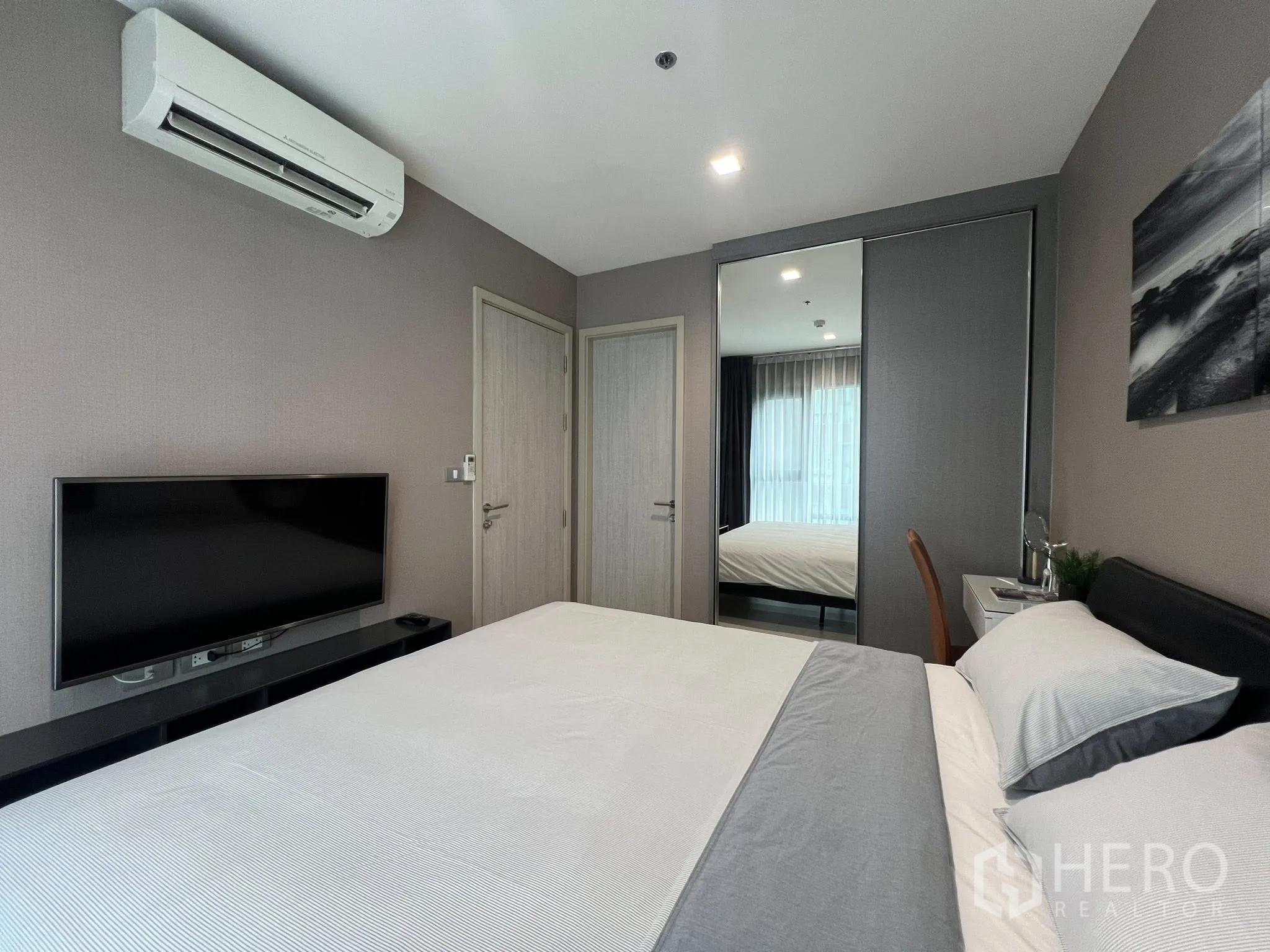 Condominium for rent in Khlong Toei, Bangkok - Bedroom with queen bed, flat-screen TV on console, air-conditioning, and mirrored wardrobe.