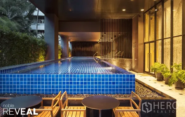 Condominium for rent or sale in Watthana, Bangkok - Condominium facilities with an elevated blue-tile swimming pool, seating area and greenery.