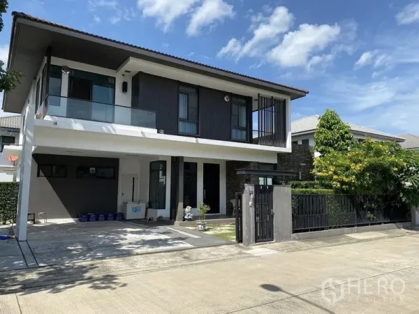 Detached House for rent or sale in Bang Phli, Samut Prakan - Modern two-storey detached house exterior with covered carport, gate and driveway under blue sky.