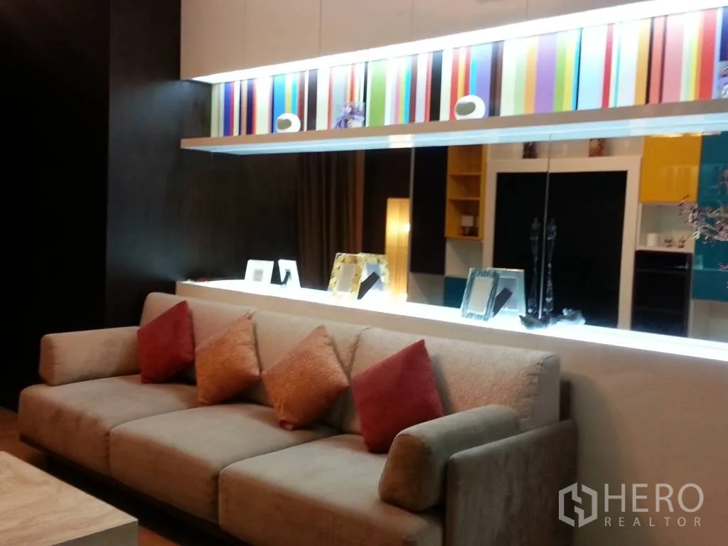คอนโด ให้เช่าในKhlong San, Bangkok - ห้องนั่งเล่นสไตล์โมเดิร์น โซฟาสีเบจ ผนังไฮไลต์สีสันพร้อมชั้นวางของมีไฟ