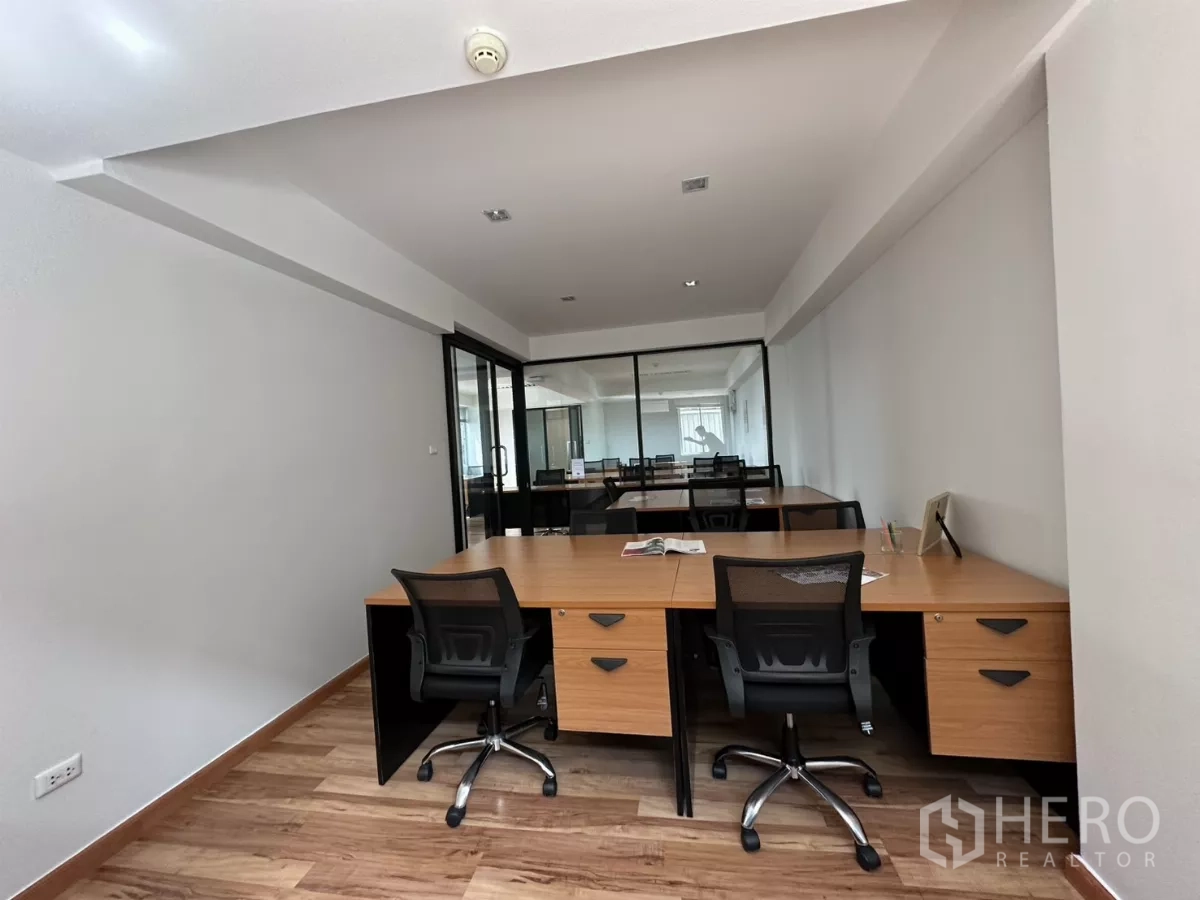 办公空间 出租在Watthana, Bangkok - 细长房间摆放成对工位，玻璃隔断通向主办公区。