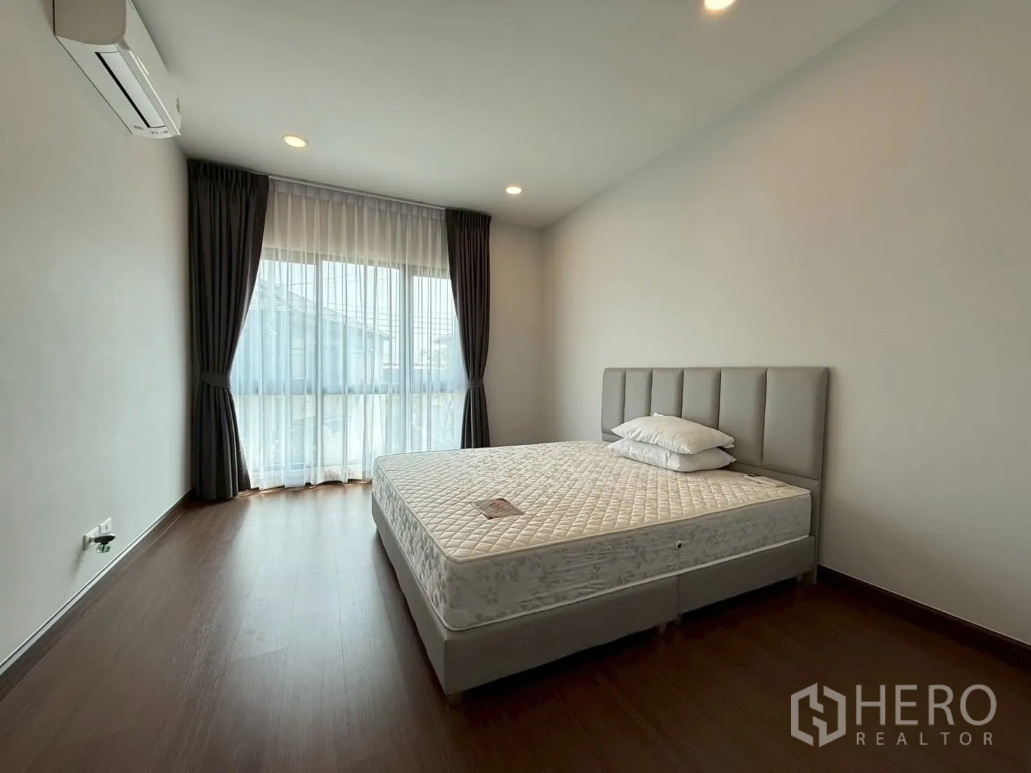 Townhouse for rent - Sunlit bedroom with queen bed, laminate wood flooring and wide windows.