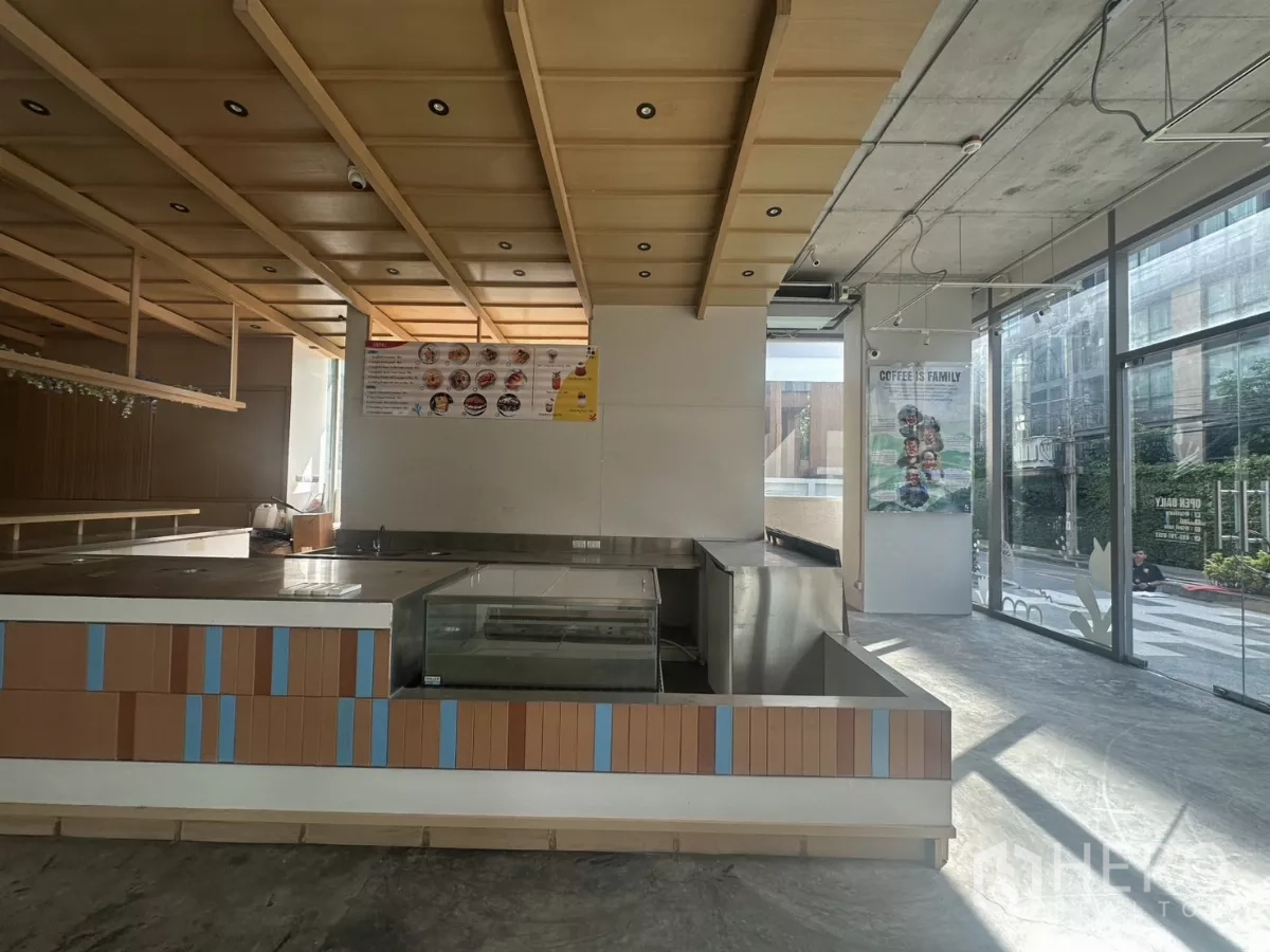 พื้นที่ขายปลีก ให้เช่า - เคาน์เตอร์มุมพร้อมตู้แช่ โทนไม้ และหน้าต่างติดถนนรับแสงธรรมชาติ