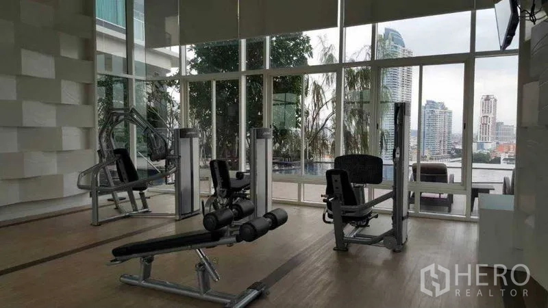 Condominium for rent in Bang Kho Laem, Bangkok - Fitness center with weight machines and river-facing windows.