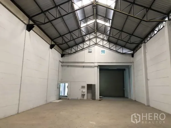 Warehouse for rent in Lat Lum Kaeo, Pathum Thani - Spacious warehouse hall showing skylights, high ceiling and a loading roller door.