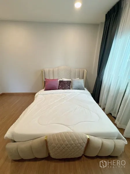Detached House for rent or sale in Bang Phli, Samut Prakan - Guest bedroom with beige upholstered bed and soft lighting.