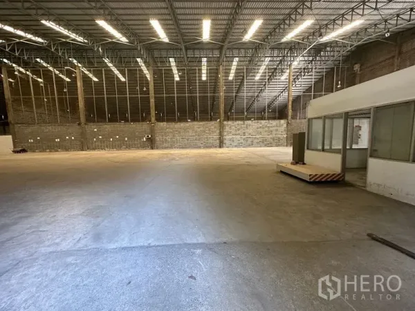 Warehouse for rent in Suan Luang, Bangkok - Open storage area with bright lighting and a portable office module.